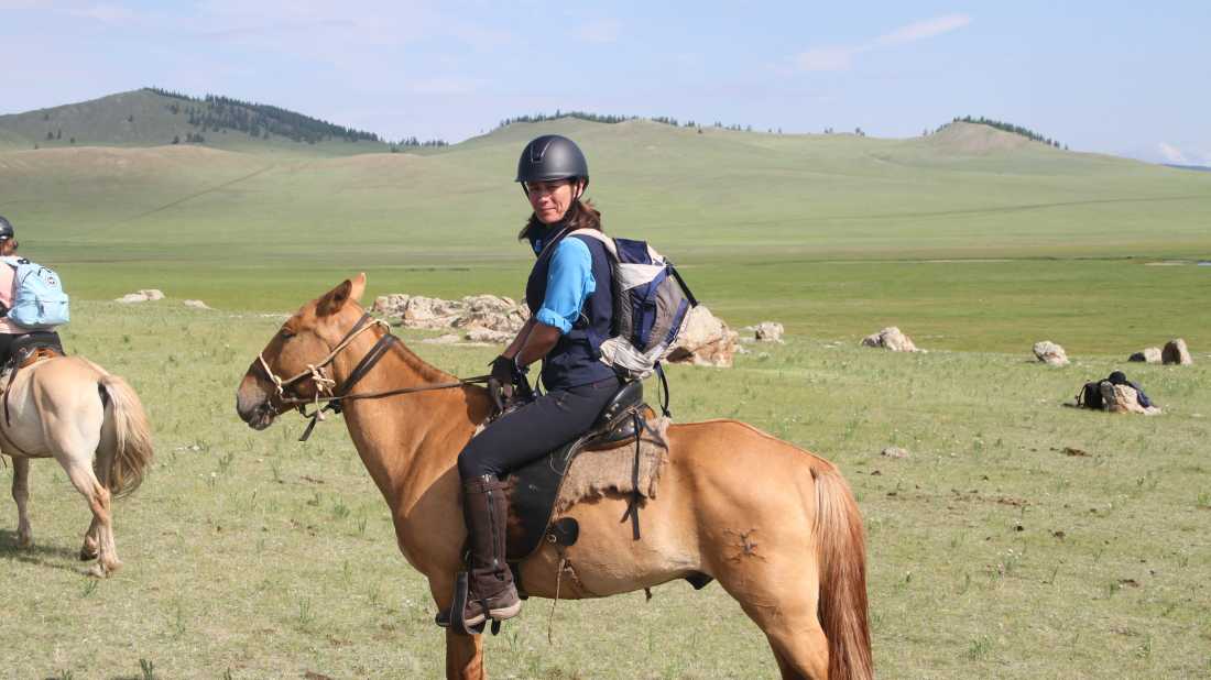 World Expeditions Rider on horseback crossing Mongolia’s green steppe, deep in nomadic country